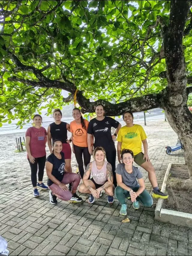 Grupo de alunos sob uma árvore, na orla